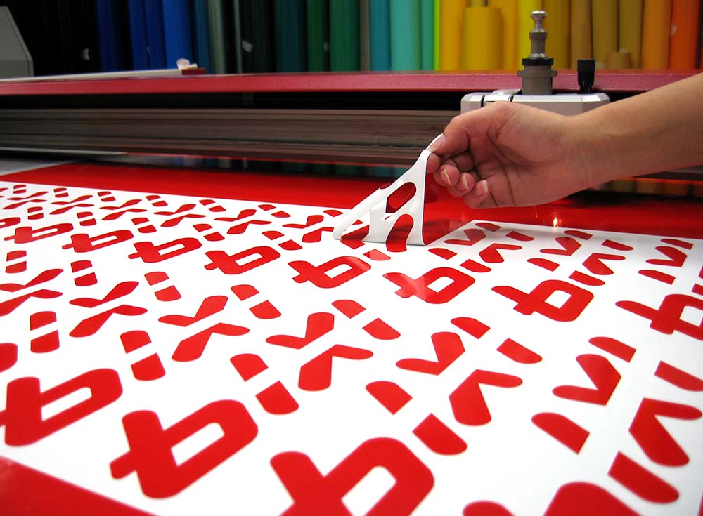 Échenillage de stickers en vinyle rouge découpés au traceur de découpe